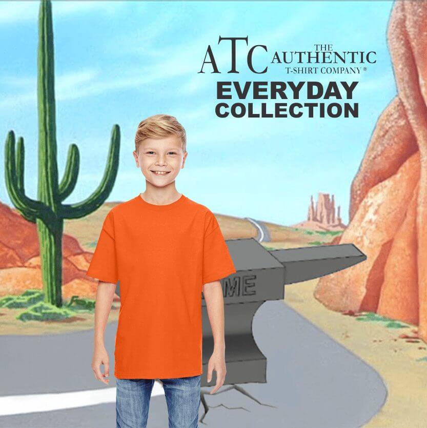 Smiling young boy wearing a plain bright orange short-sleeve t-shirt from the Everyday Collection by The Authentic T-Shirt Company, standing against a cartoon desert background with cacti and rock formations