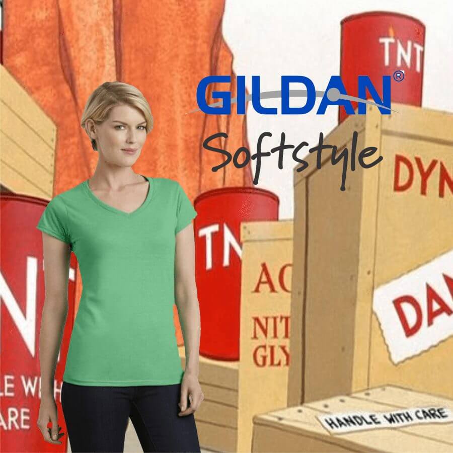 Woman wearing a fitted green V-neck short-sleeve T-shirt from Gildan Softstyle, standing against a cartoon-style background with TNT barrels and wooden boxes labeled with warning signs.