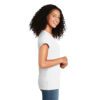 Smiling woman with curly hair wearing a plain white T-shirt and blue jeans, standing in profile with hands clasped.