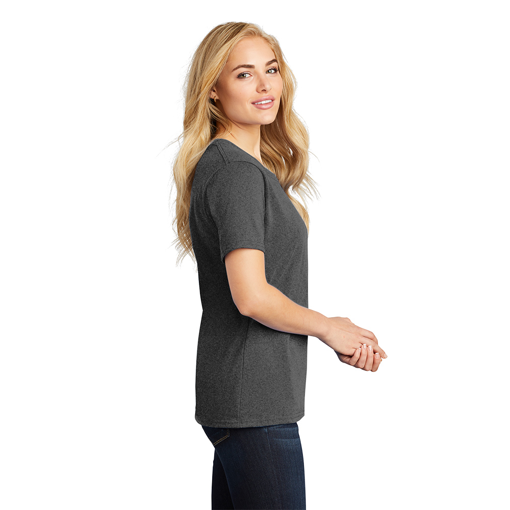 Blonde woman wearing a dark gray short-sleeve T-shirt and dark jeans, standing in profile with hands clasped