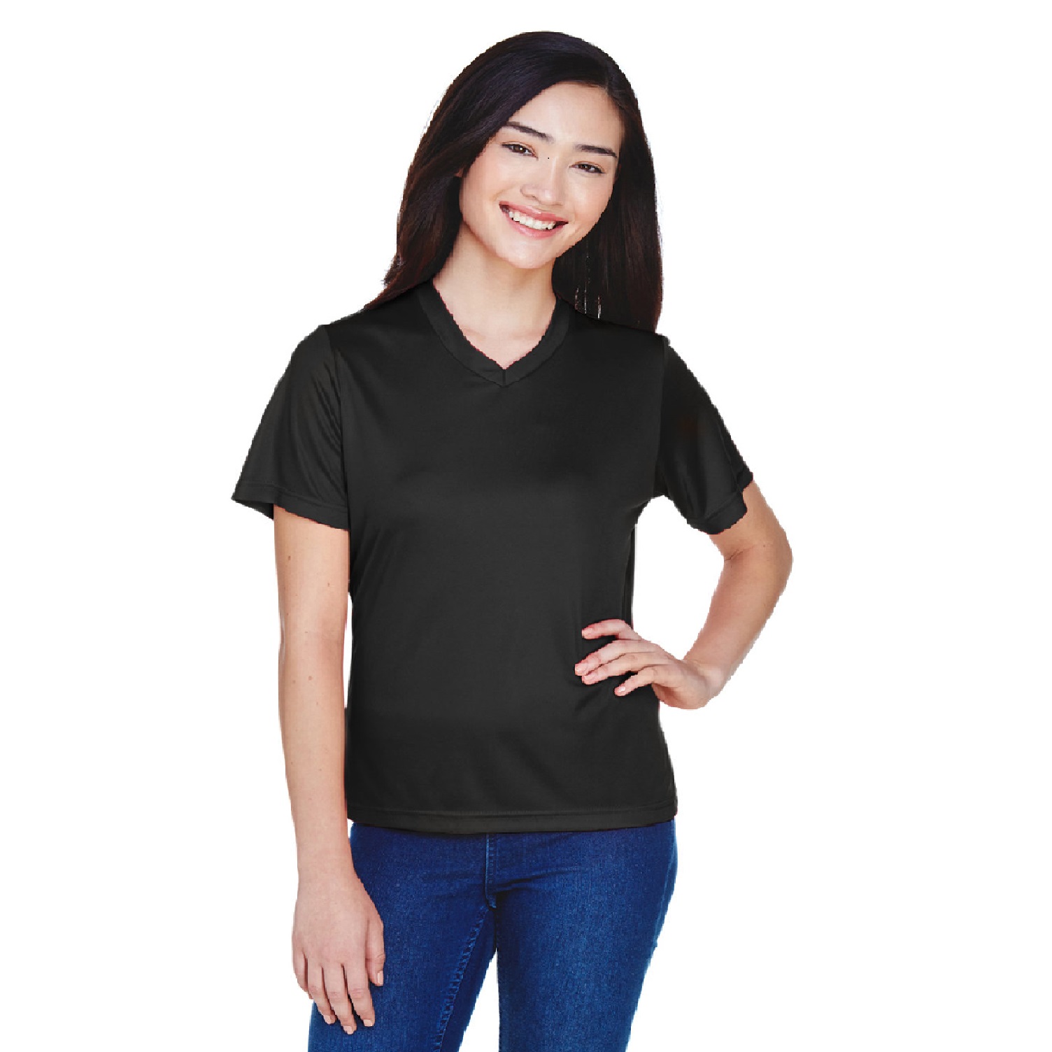 A smiling woman with long dark hair wearing a plain black V-neck short-sleeve shirt and blue jeans, posing with one hand on her hip.