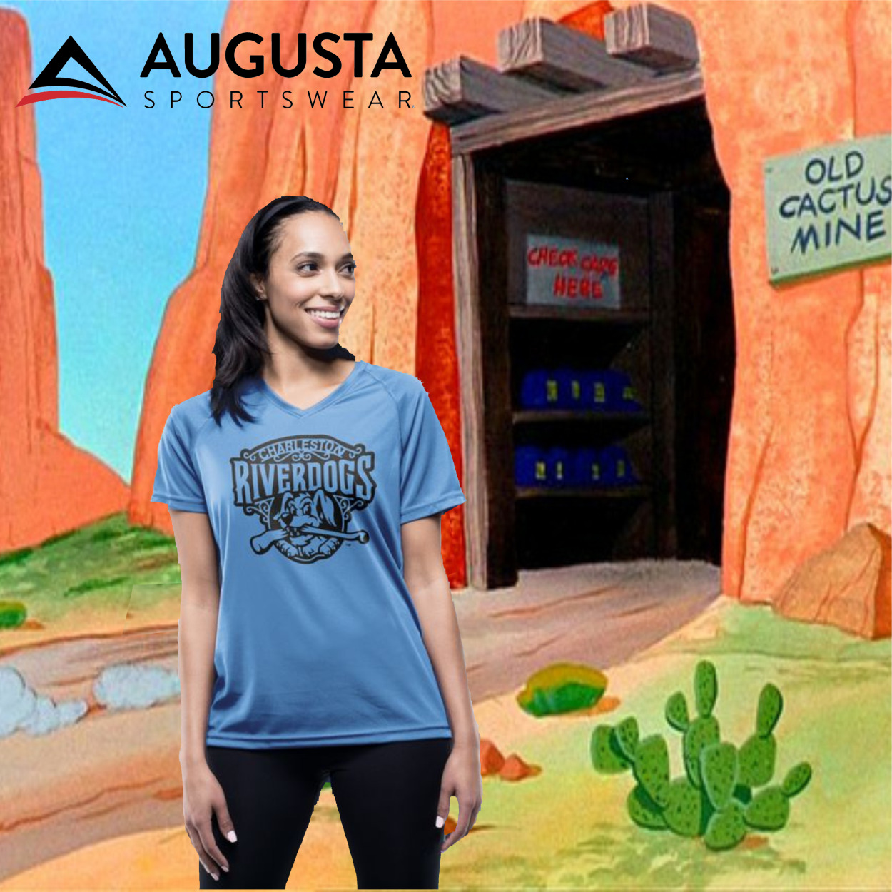 attain_ladies_cover Woman wearing a light blue V-neck shirt with 'Charleston Riverdogs' printed logo, standing against a colorful cartoon desert background with an old mine entrance and cactus