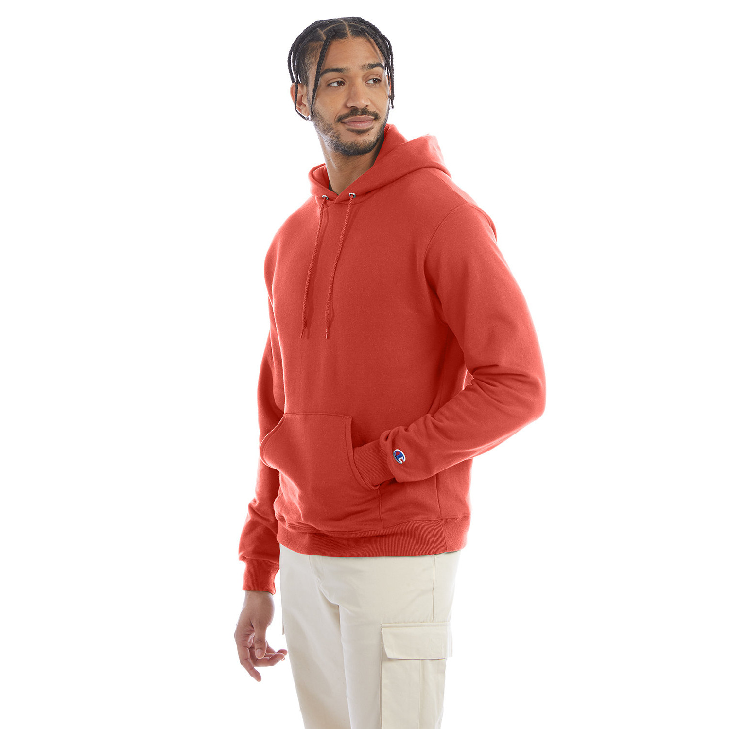 champion_hood_cover_front Man with braided hair wearing a red hoodie with a front pocket and beige cargo pants, looking to the side against a white background.
