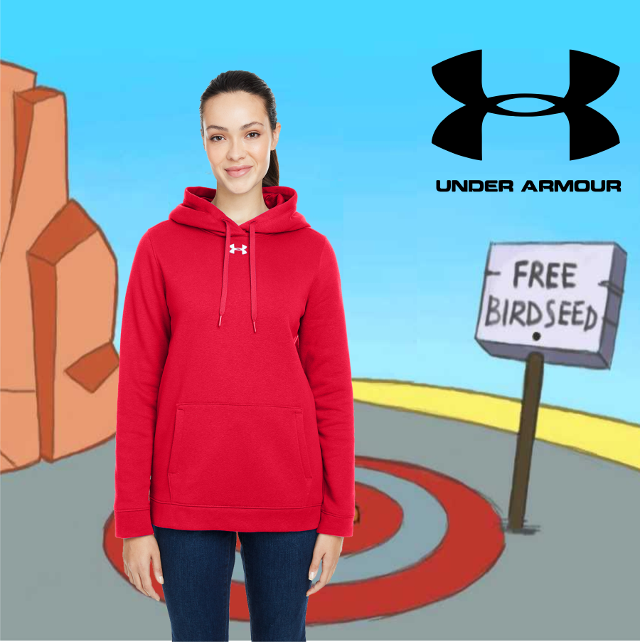ua_ladies_cover_hustle_hoodie A young woman wearing a red Under Armour hoodie stands in front of a cartoon scene with rock formations, a target on the ground, and a sign that reads 'Free Birdseed' with a large Under Armour logo in the sky.