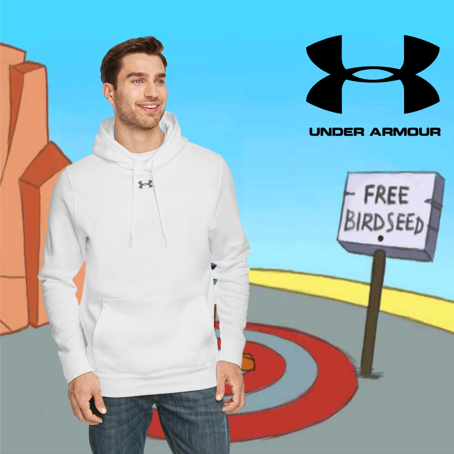 Smiling man wearing a white Under Armour hoodie standing in front of a cartoon background with rocks, a target on the ground, a sign reading 'FREE BIRDSEED,' and the Under Armour logo in the sky.