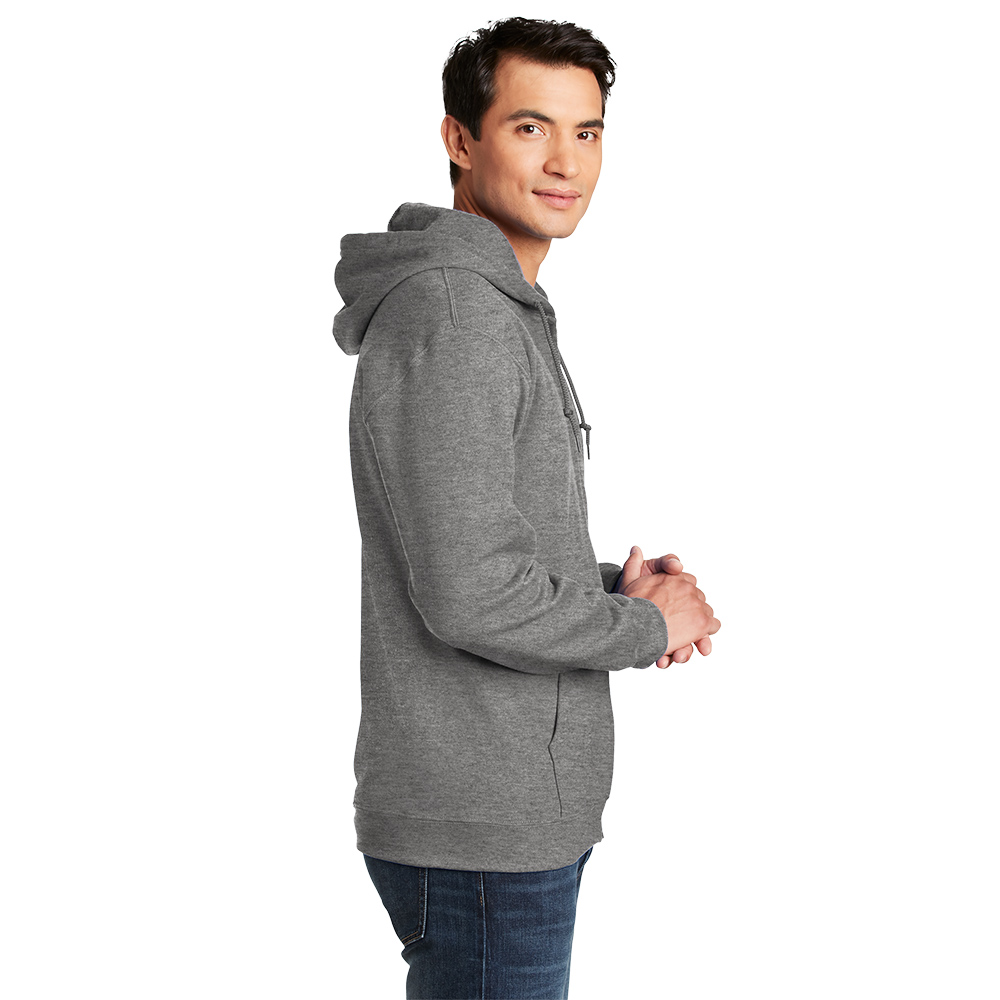 18600_graphiteheather_model_side Side view of a man wearing a gray hooded sweatshirt and blue jeans, standing with hands clasped, looking at the camera with a slight smile.