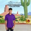 cover_front Smiling man wearing a purple polo shirt standing in front of a desert cartoon background with cacti and rock formations, with text above reading "ATC The Authentic T-Shirt Company Performance Collection" and a yellow box labeled "Acme Batman's Outfit" on the right side.