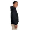 mnp_gildan_heavyblend_hoodie_cover_2 Side view of a smiling man wearing a black hoodie and beige pants against a white background.