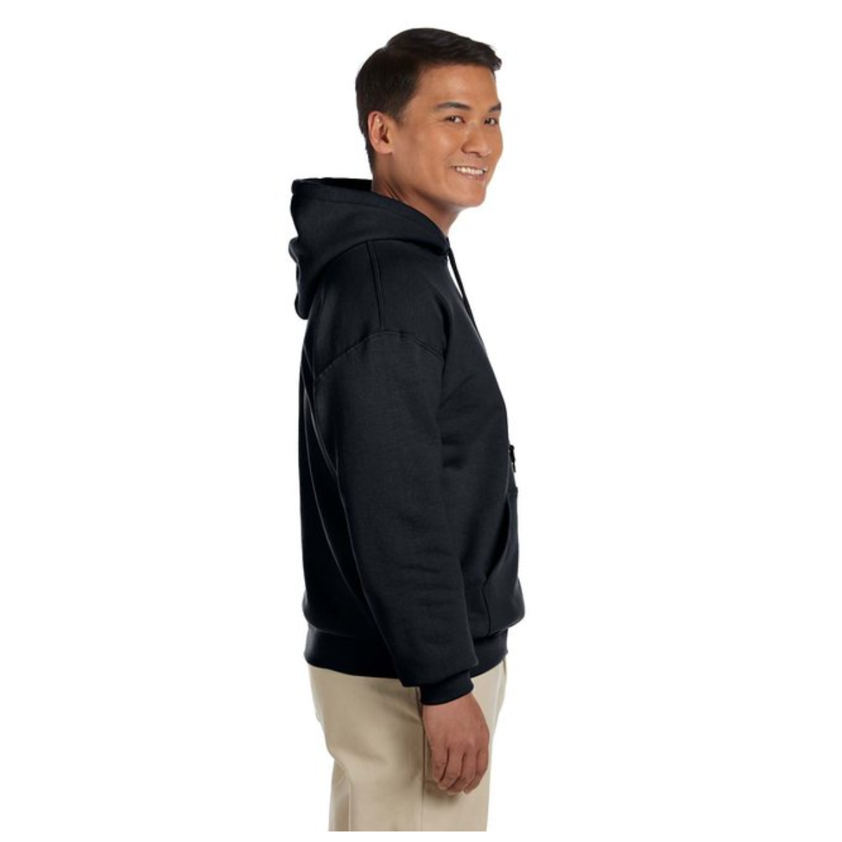 Side view of a smiling man wearing a black hoodie and beige pants against a white background.