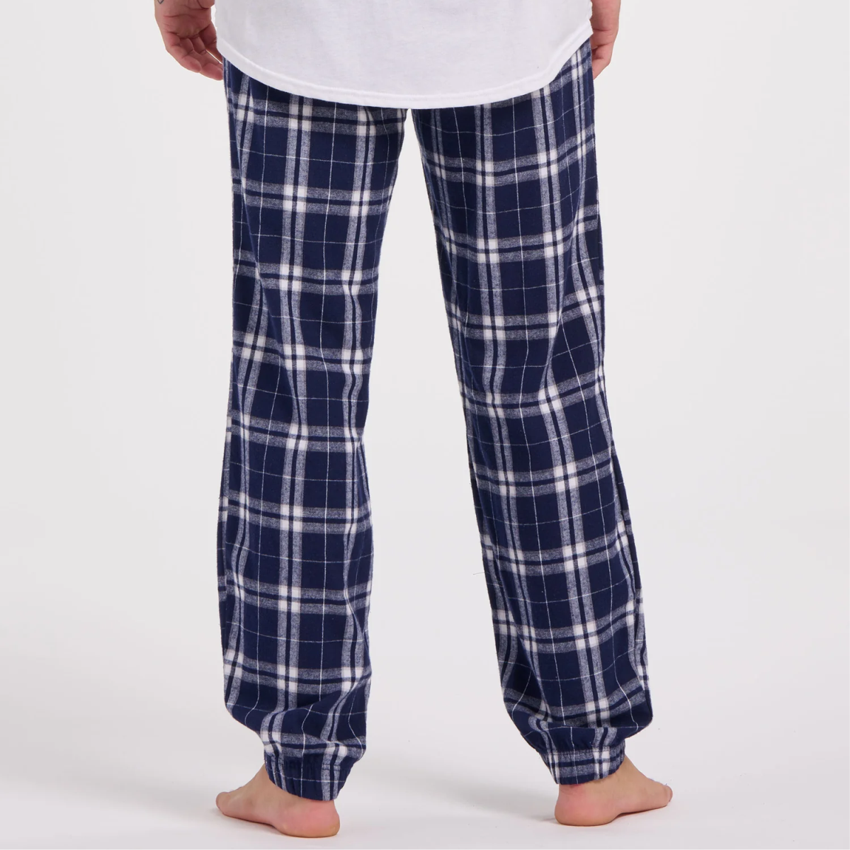Back view of a person wearing the Boxercraft BM6625 navy blue plaid pajama pants paired with a relaxed white t-shirt, showcasing a cozy loungewear style ideal for home relaxation.