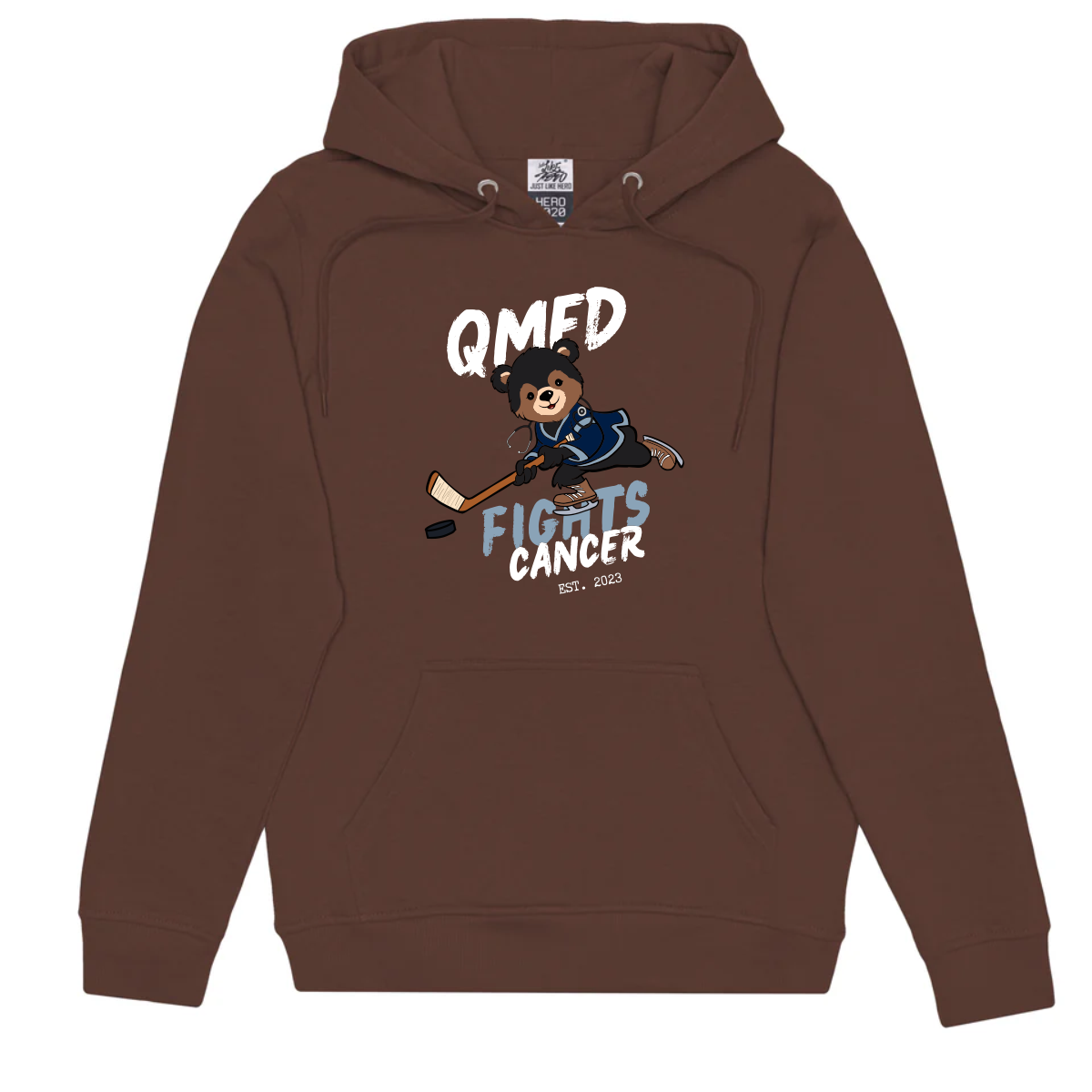 Just Like Hero 2020 55% Cotton 40% Polyester 5% Rayon brown hoodie featuring a playful bear character playing hockey, with the text "QMED FIGHTS CANCER" and "EST. 2023" prominently displayed, promoting cancer awareness initiatives.
